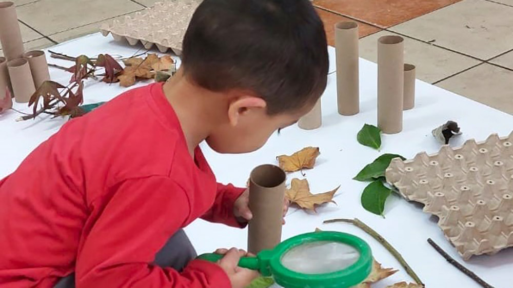 Un niño juega con una lupa explorando el mundo.